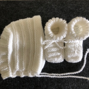 Weiße handgestrickte Babyschuhe ohne Naht und Babyhaube
